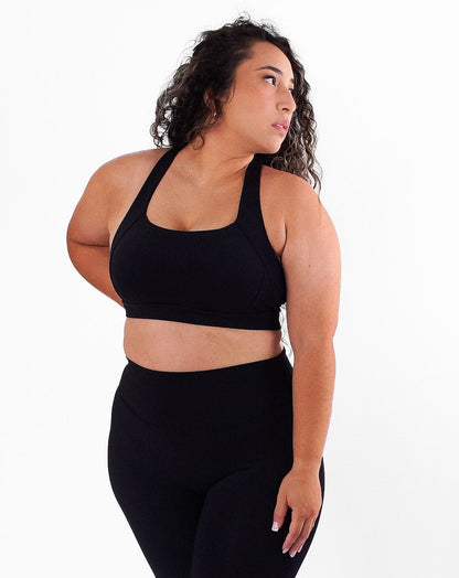 Woman wearing a black sports bra and leggings on a white background