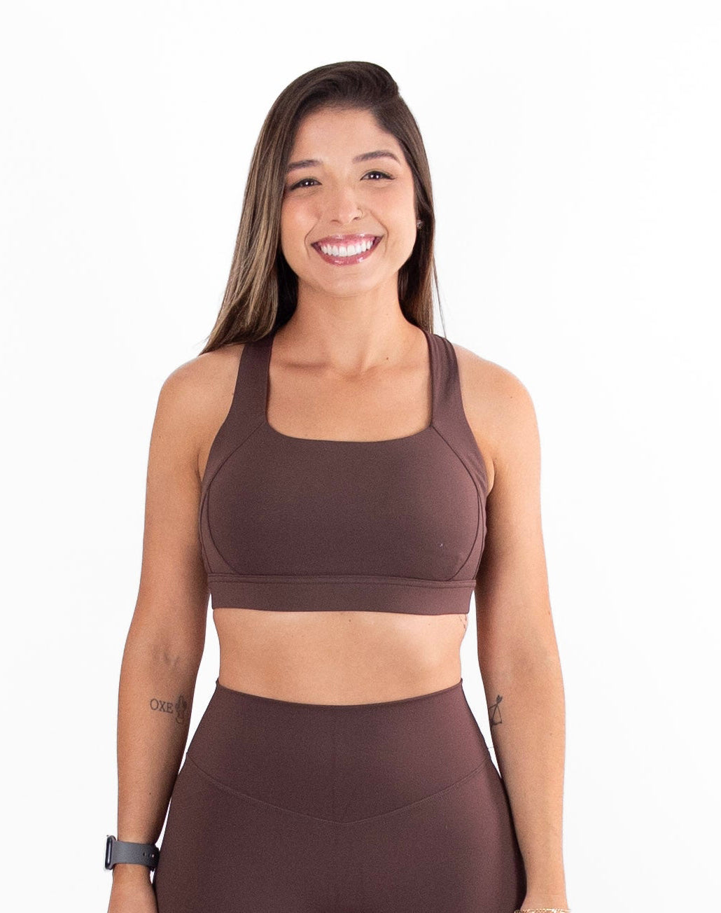 Woman wearing a brown sports bra and leggings set on a white background