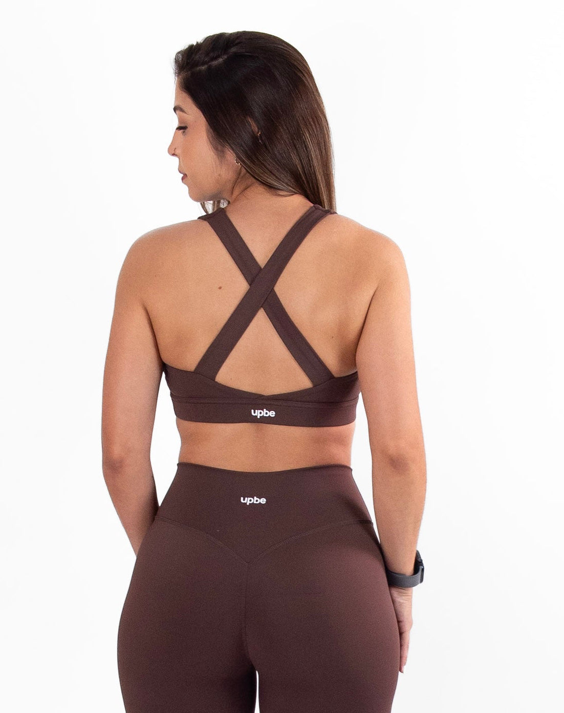 Woman wearing a brown sports bra and leggings set on a white background