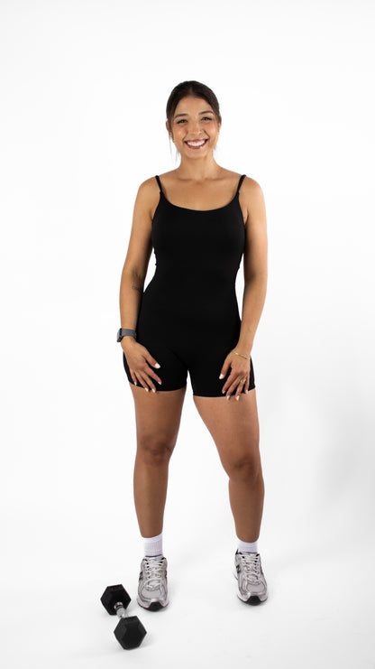 Woman wearing a black jumpsuit with dumbbells on a white background