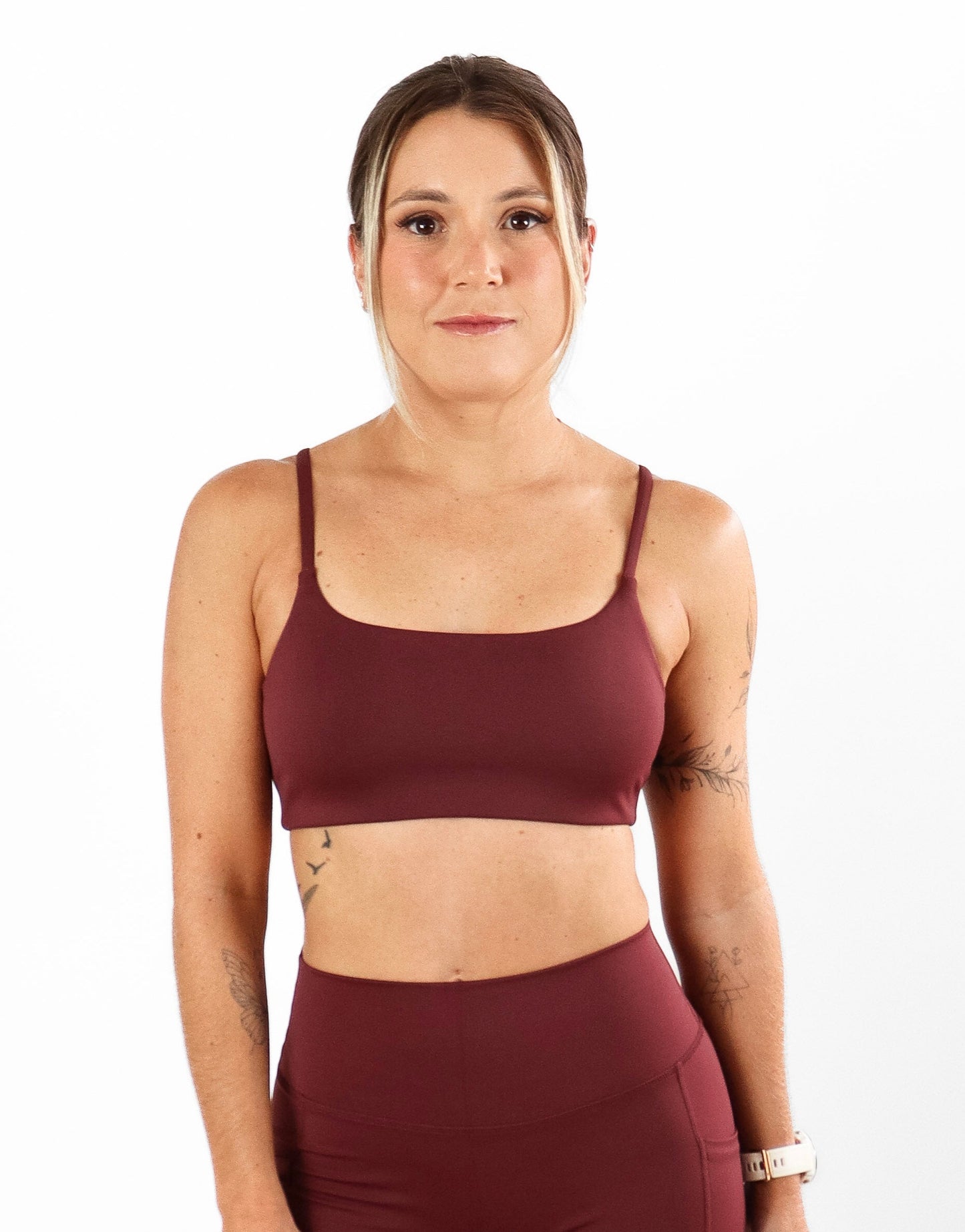 Woman wearing a burgundy athletic outfit on a white background