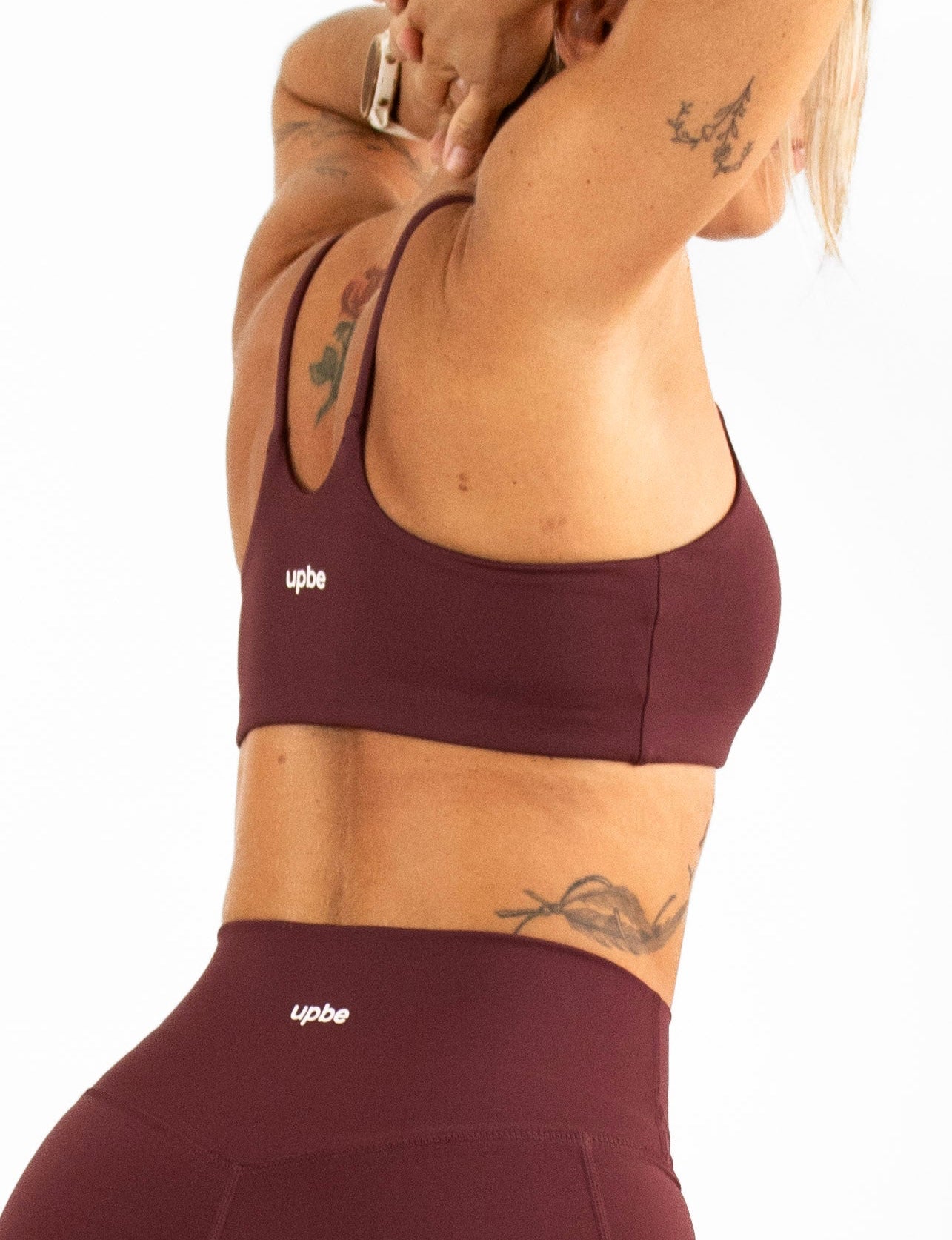 Woman wearing a burgundy sports bra and shorts on a white background