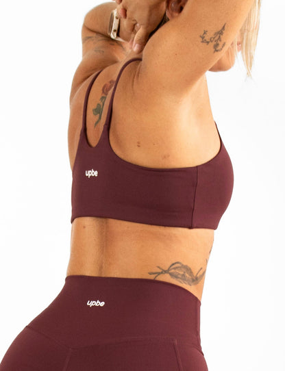 Woman wearing a burgundy sports bra and shorts on a white background