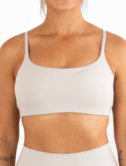 Woman wearing a grey sports bra and shorts on a white background
