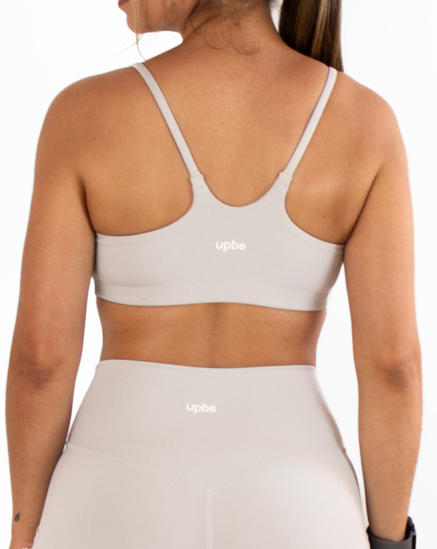 Woman wearing a grey sports bra and shorts set on a white background