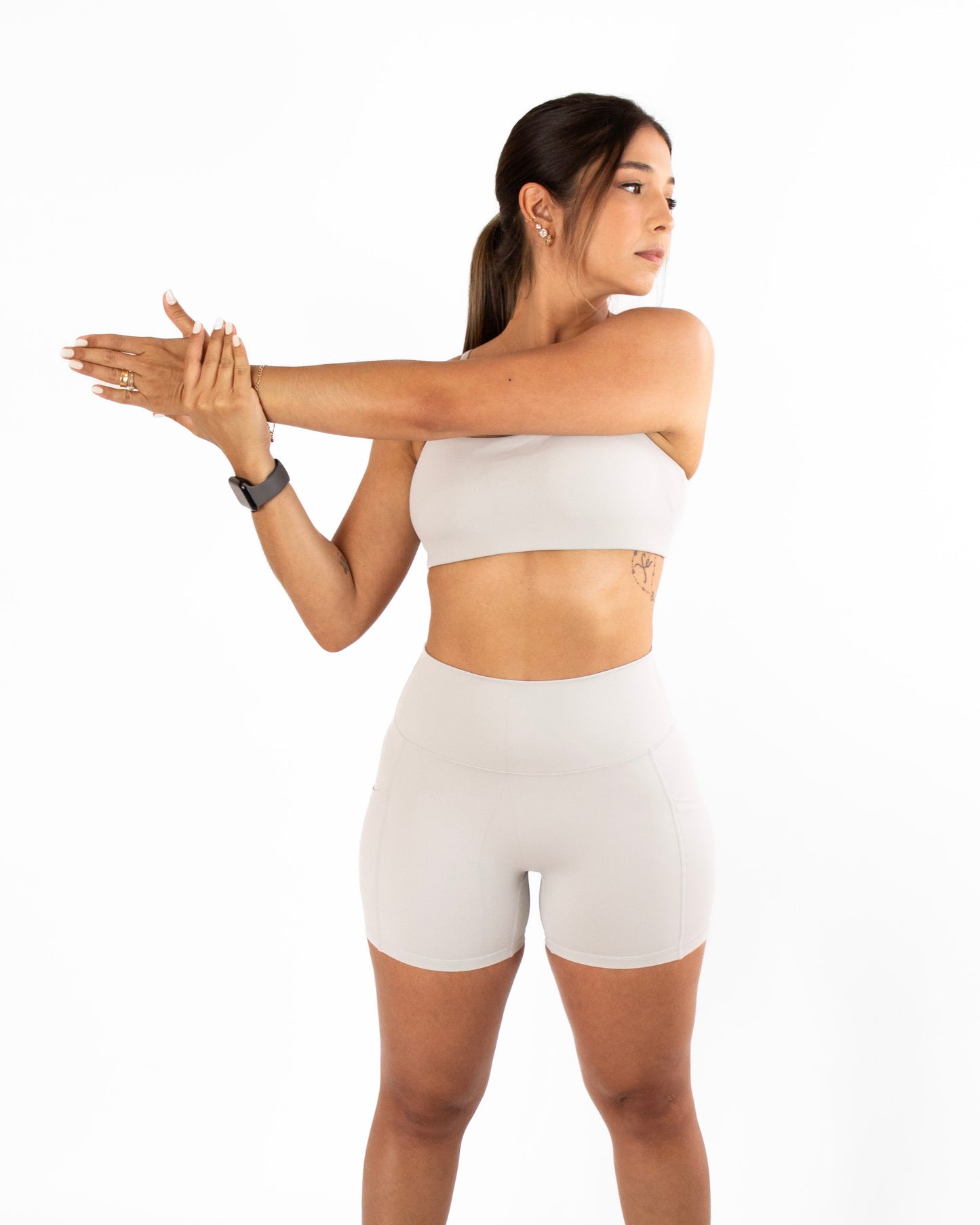 Woman in grey athletic wear stretching on a white background