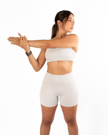 Woman in grey athletic wear stretching on a white background