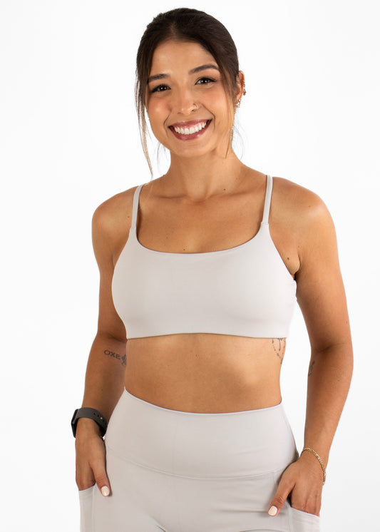 Woman wearing a beige sports bra and shorts set on a white background