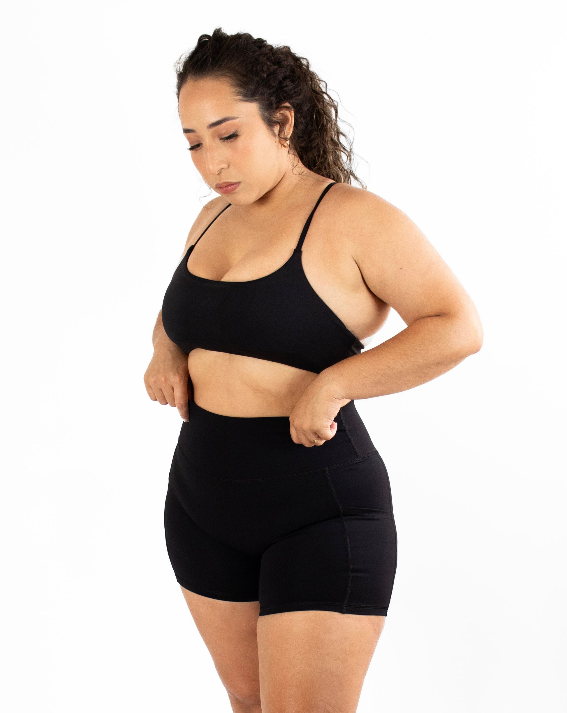 Woman wearing a black sports bra and shorts set on a white background