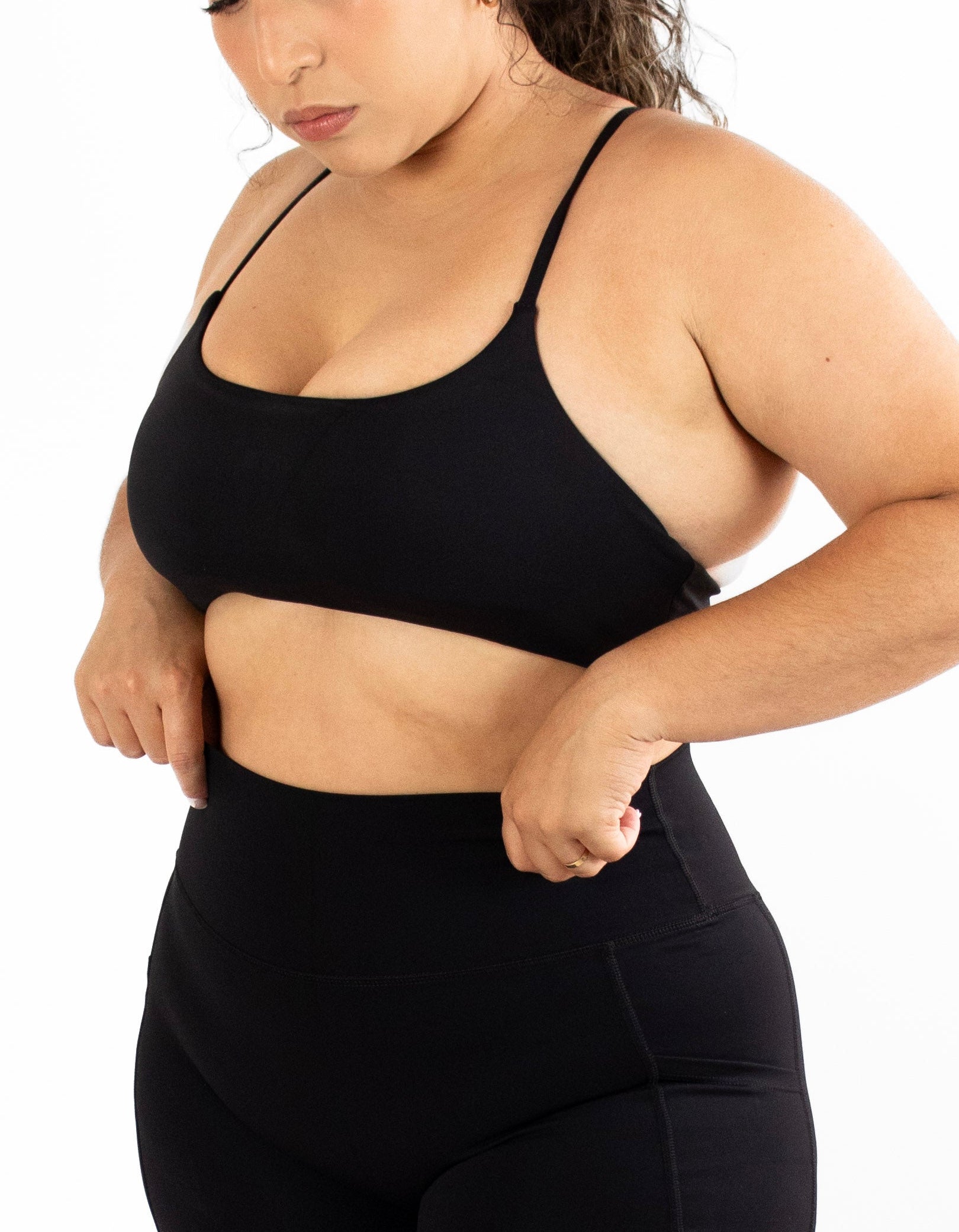 Woman wearing a black sports bra and shorts set on a white background